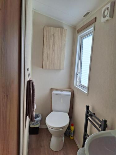 a small bathroom with a toilet and a window at Beachside Heacham in Heacham