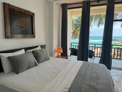 a bedroom with a bed with a view of the ocean at Turtle Beach House in Batigama