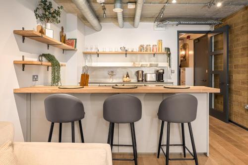 a kitchen with a counter with three bar stools at Be London - The Southwark Residences in London