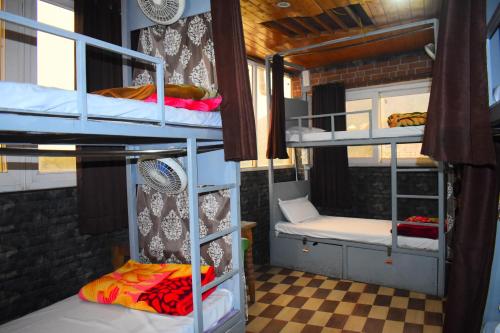 a room with three bunk beds and a checkered floor at Hotel V N Ganga in Rishīkesh