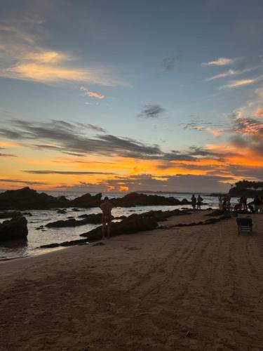 a group of people standing on the beach at sunset at Turtle Beach House in Batigama