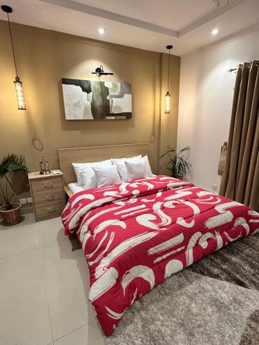 a bedroom with a red and white comforter on a bed at Staye in Islamabad