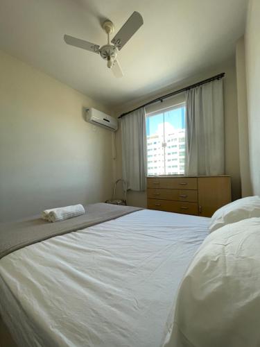 a bedroom with a white bed with a ceiling fan at Dois quartos centro in Ubá