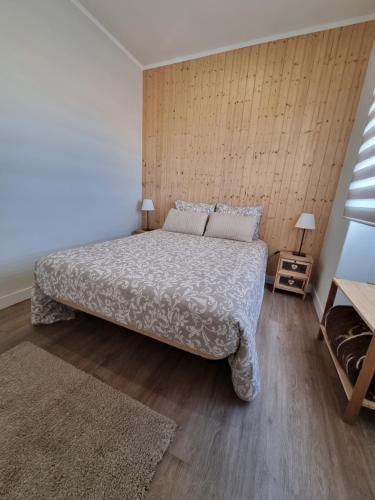 a bedroom with a large bed and a wooden wall at Family Surf Home - Casa do Sol in Mafra