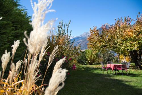 a table and chairs in a garden with mountains in the background at Hotel Garni Katnau in Schenna