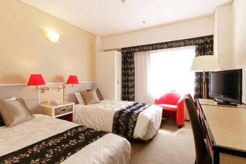 a hotel room with two beds and a television at The Celecton Fukushima in Fukushima