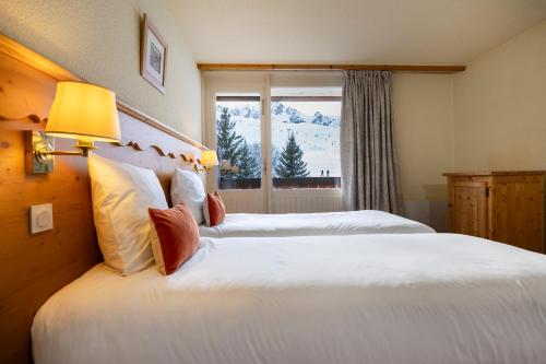 a hotel room with two beds and a window at Crystal Hôtel in Courchevel