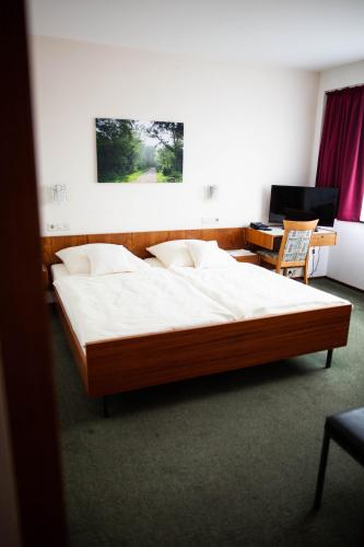 a large bed in a room with a desk at Hotel-Cafe Römer in Siegen