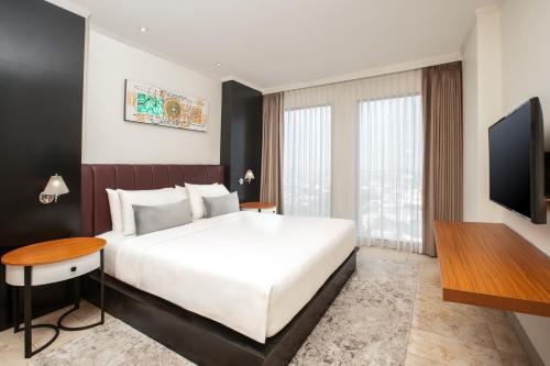 a bedroom with a large bed and a flat screen tv at Aryaduta Palembang in Palembang