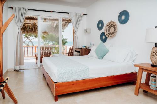 a bedroom with a bed and a view of the ocean at Hotel Carey Beach Baru in Barú