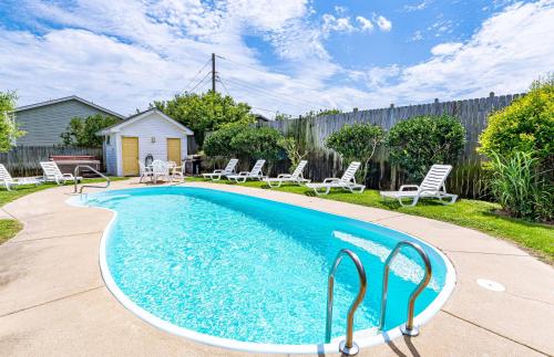 a swimming pool in a yard with chairs and a fence at Sunny Delight - KDH MP 7, Ocean View, 130 Yds to Beach, Pool, Hot Tub, Pets OK, Flex Stays in Kill Devil Hills