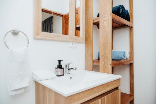 a bathroom with a sink and a wooden shelf at Hotel Carey Beach Baru in Barú