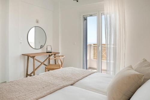 a white bedroom with a bed and a mirror at Lourdas White Villa in Kefallonia
