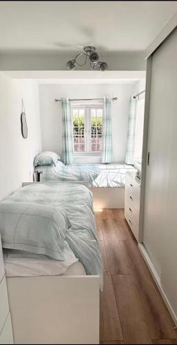 a white bedroom with two beds and a window at Coach house in Enderby