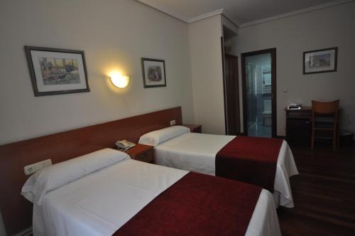 a hotel room with two beds and a table at Pension Alameda in San Sebastián