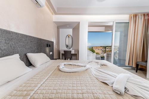 a bedroom with a large white bed with a large window at Villa Naisy in Tsilivi