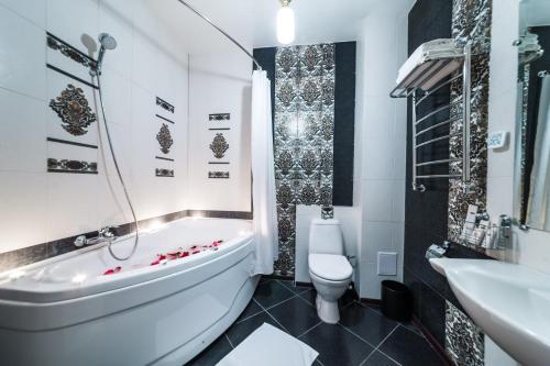 a bathroom with a tub and a toilet and a sink at Hotel Kupecheskiy Dom in Tomsk