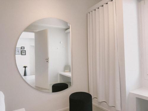 a bathroom with a round mirror and a black chair at AELIA Tinos in Tinos