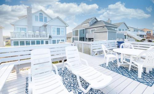 a white deck with white chairs and a table at Fly Boys - Nags Head MP 12.5, Oceanfront, Ocean View, Elevator, Pool Table, Hot Tub, YR Flex in Nags Head