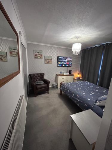 a bedroom with a bed and a chair and a tv at Park House in Leicester
