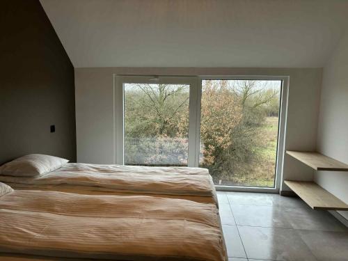 a bedroom with a bed and a large window at L'ancien rucher in Hotton