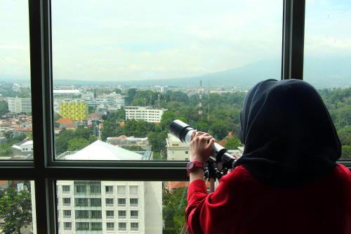 a person looking out of a window with a camera at Swiss-Belhotel Bogor in Bogor