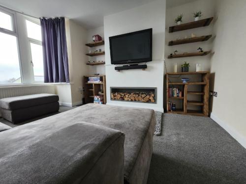 a living room with a tv and a fireplace at Bank End Cottage in Almondbury