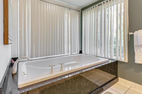 a bath tub in a bathroom with white blinds at Riverfront Savannah Getaway w/ Pool & Dock! in Savannah