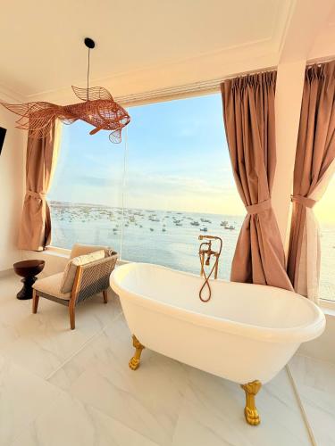 a bath tub in a bathroom with a large window at Bay View Resort & Villas Mũi Né in Phan Thiet