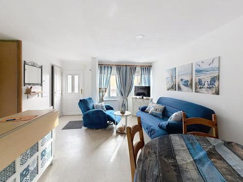 Una sala de estar con un sofá azul y sillas. en Maison des dunes, en Fort-Mahon-Plage