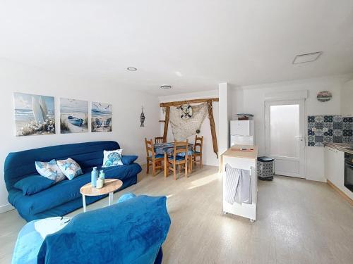 Una sala de estar con un sofá azul y una cocina. en Maison des dunes, en Fort-Mahon-Plage