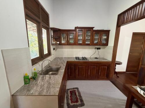 a kitchen with wooden cabinets and a sink and a window at Gurugoda Riverside Villa in Ruwanwella