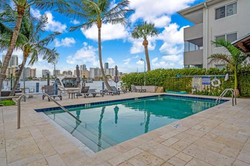 a swimming pool with palm trees and a building at Waterfront Luxe Condo - Close to beach in Hallandale Beach