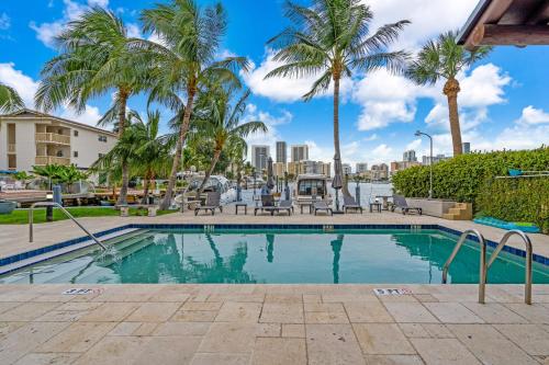 a swimming pool with palm trees and a city at Waterfront Luxe Condo - Close to beach in Hallandale Beach