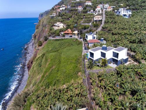 an aerial view of a house on a hill next to the ocean at Quinta Golfinho in Arco da Calheta