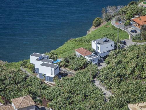 an aerial view of a house on a hill next to the ocean at Quinta Golfinho in Arco da Calheta