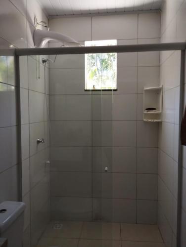 a bathroom with a glass shower with a window at Recanto da LM in Foz do Iguaçu