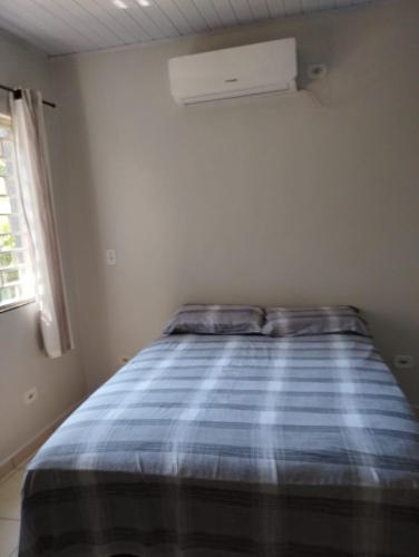 a bedroom with a bed with a blue plaid blanket at Recanto da LM in Foz do Iguaçu