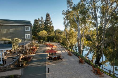 a street with tables and umbrellas next to a river at River Terrace Inn in Napa