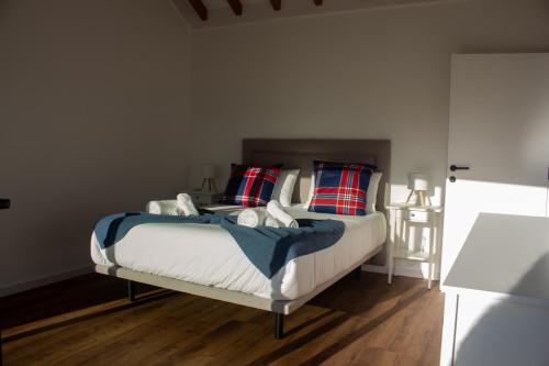 a bedroom with a bed with red and blue pillows at Quinta das Candeias - Casa da Bé in Arcos de Valdevez