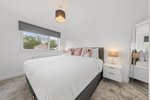 a white bedroom with a large bed and a window at Large 5 Bedroom House Perfect For Group Stays - Free Parking - Near Glasgow - Perfect For Contractors in High Blantyre