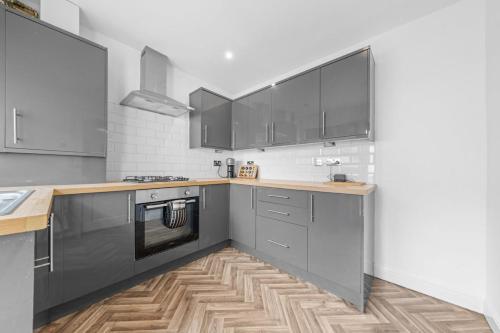 a kitchen with black cabinets and a wooden floor at Large 5 Bedroom House Perfect For Group Stays - Free Parking - Near Glasgow - Perfect For Contractors in High Blantyre
