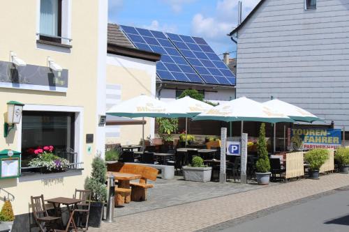 a patio with tables and umbrellas in front of a building at Hotel & Restaurant Hüllen in Barweiler