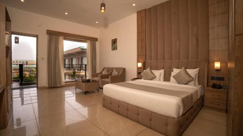 a bedroom with a large bed and a balcony at Corbett Elegant Retreat Jim Corbett in Rāmnagar