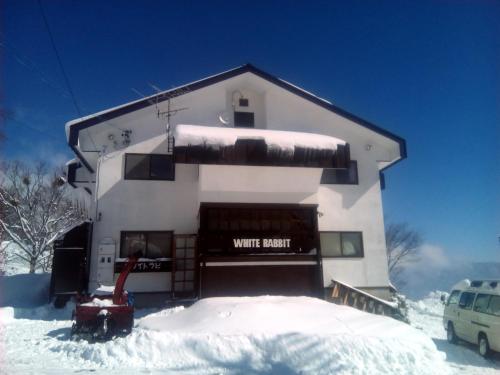 a white building with snow in front of it at White Rabbit Madarao in Iiyama