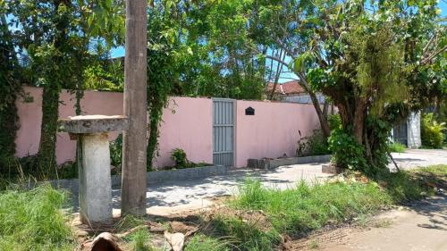 a pink house with a fence and a tree at Bruno Pereira in Guarujá