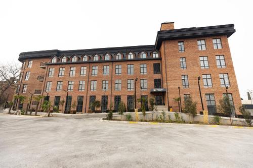 ein großes Backsteingebäude mit einem großen Parkplatz in der Unterkunft Imaret Hotel in Ganja
