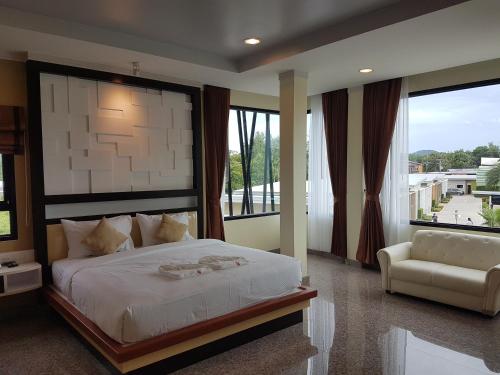 a bedroom with a bed and a chair and windows at Smile Resort Thungsong in Thung Song