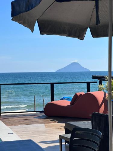 a view of the ocean from a deck with an umbrella at Casatua Pousada in Juquei