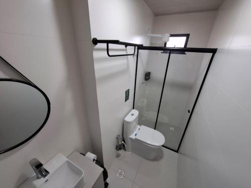 a white bathroom with a toilet and a mirror at Miraflores Hotel in Macapá
